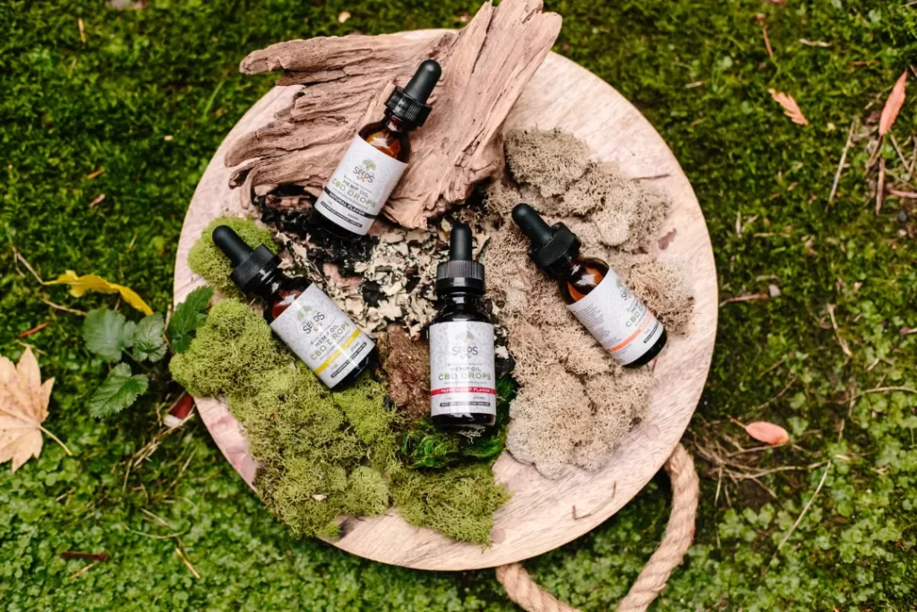 CBD oil drops with dried and fresh sea moss on a wooden plate.