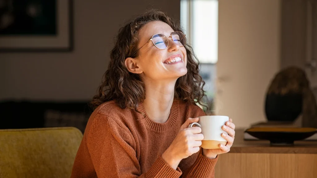 Happy and relaxed girl smiling while taking coffee